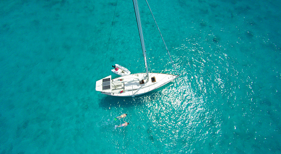 Vista aérea de una pareja esnórquel por barco de vela en el Caribe photo