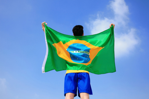 Excited man holding a brazil flag with blue sky