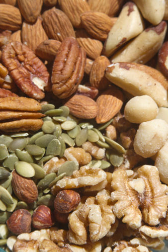 A close up of healthy, raw, organic nuts and seeds, incuding walnuts, almonds, pumpkin seeds, macademia nuts, pecans, filberts and brazil nuts