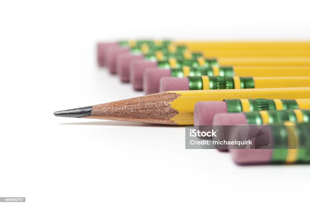 Row of pencils Close-up of a row of yellow pencils with one sharpened pencil sticking out of the row on a white background. Shot with a shallow depth of field. Bizarre Stock Photo