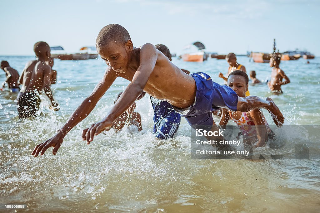 Playing kids on the beach of Stone Town - Zanzibar Zanzibar, Tanzania - October 18, 2013: Group of kids playing in the water on the beach of Stone Town. The capital of Zanzibar. Child Stock Photo