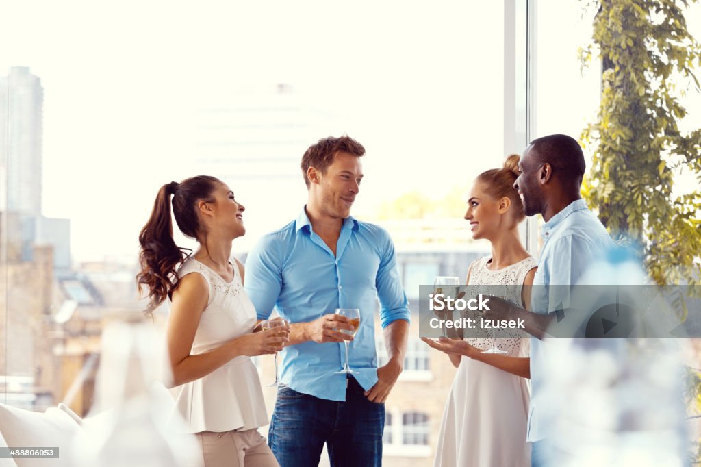 Party Group of friends enjoying their drinks in the livingroom with cityscape in the background.  Luxury Stock Photo
