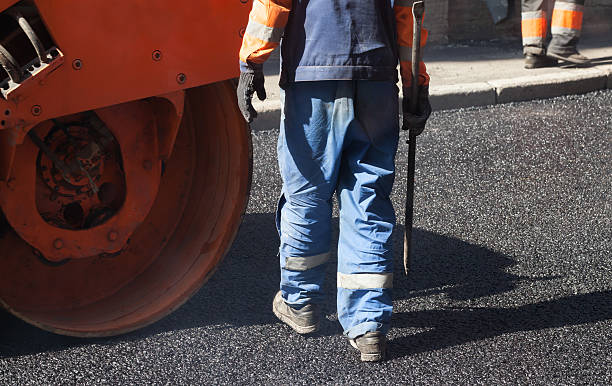 istock Asphalting, worker with a shovel near orange roller 488820196