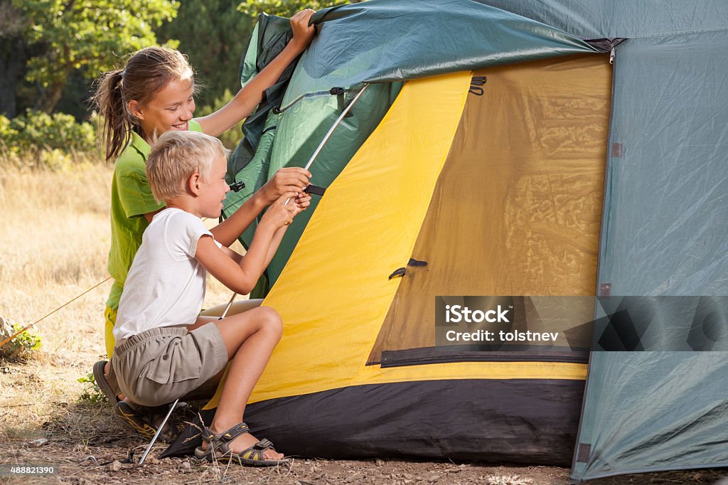 Two children setting a tent Two children setting a tent in the summer 2015 Stock Photo