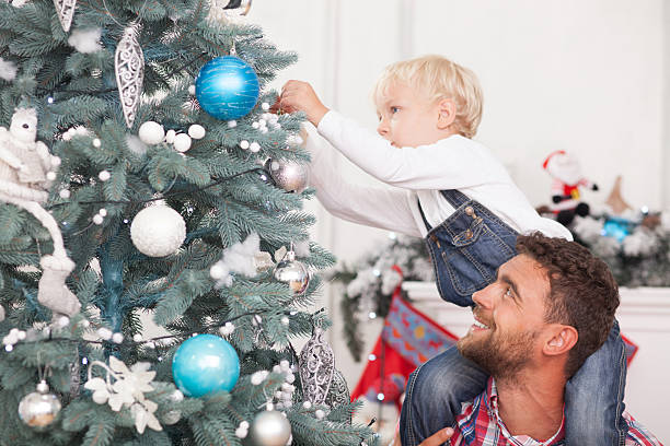 istock Pretty man and child are decorating New Year tree 488821984