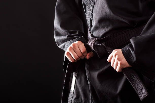 Tying the knot to his black belt Closeup of male karate fighter tying the knot to his black belt martial arts stock pictures, royalty-free photos & images