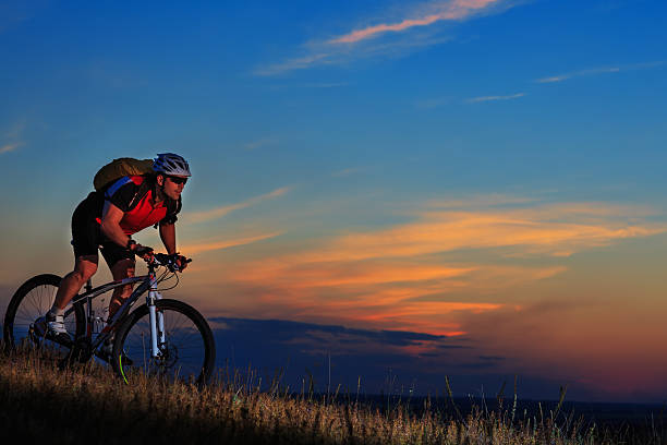 istock Silhouette of a biker and bicycle on sunset background. 488826530