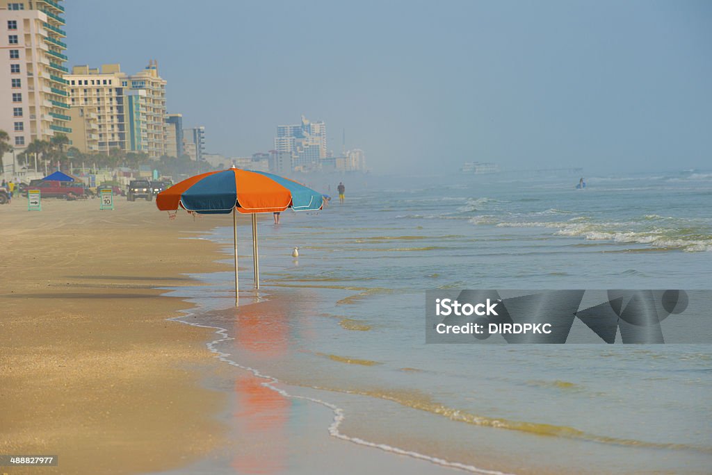 umbrellas on Daytona Beach two umbrellas in tide along Daytona beach with hi rise buildings and ocean ion background Daytona Beach Stock Photo