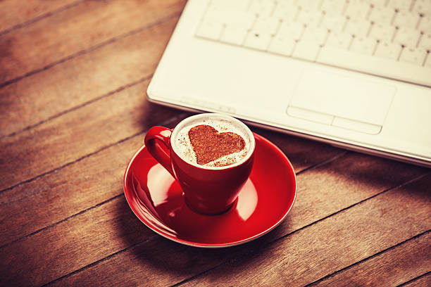 Cup of coffee and laptop on wooden table. stock photo