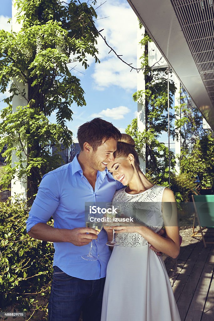 Romantic couple Outdoor portrait of affectionate couple standing with wine glasses on the terrace. High Society Stock Photo