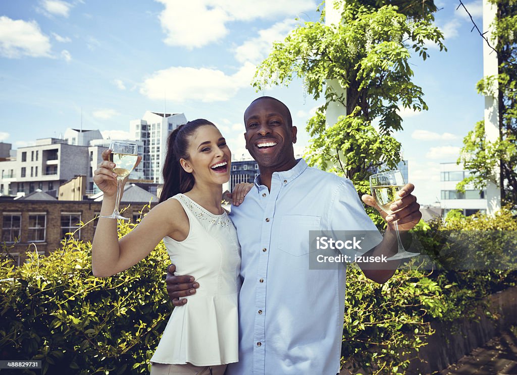 Happy couple Outdoor portrait of happy couple embracing and toasting with wine glasses with cityscape in the background. 25-29 Years Stock Photo