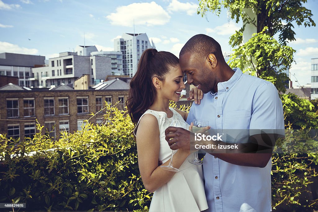 Affectionate couple Outdoor portrait of affectionate couple embracing and drinking wine with cityscape in the background. Couple - Relationship Stock Photo