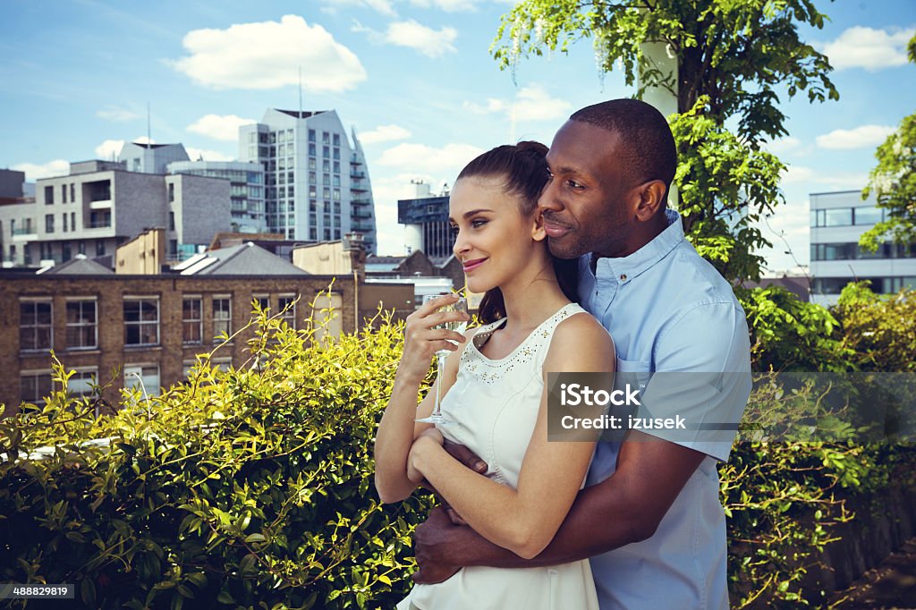 Romantic couple Outdoor portrait of affectionate couple embracing and looking away with cityscape in the background. 25-29 Years Stock Photo