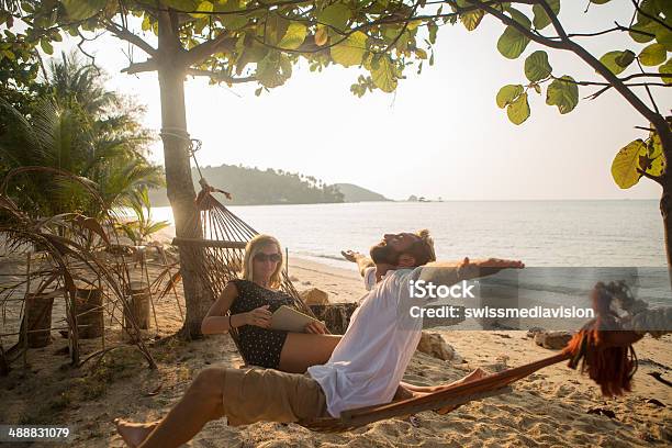 Young Couple On Hammock Relaxing And Using Digital Tablet Stock Photo - Download Image Now