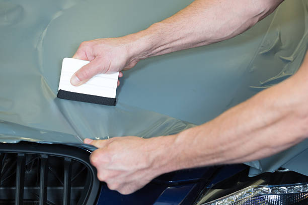istock Car wrappers using squeegee to straighten vinyl film 488832395