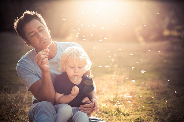 Father and son blowing dandelions