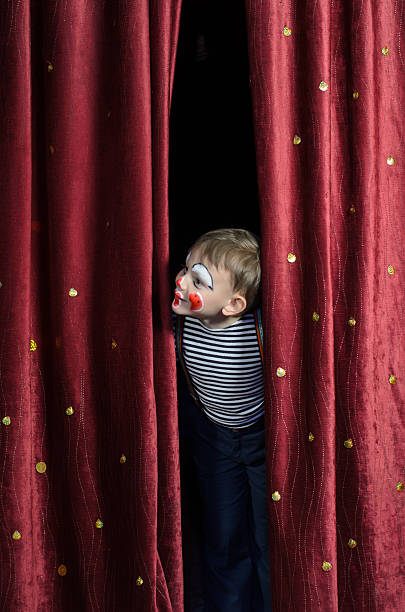 niño disfrazado payaso echar un vistazo al cortina de escenario - teatro de pantomima británico fotografías e imágenes de stock