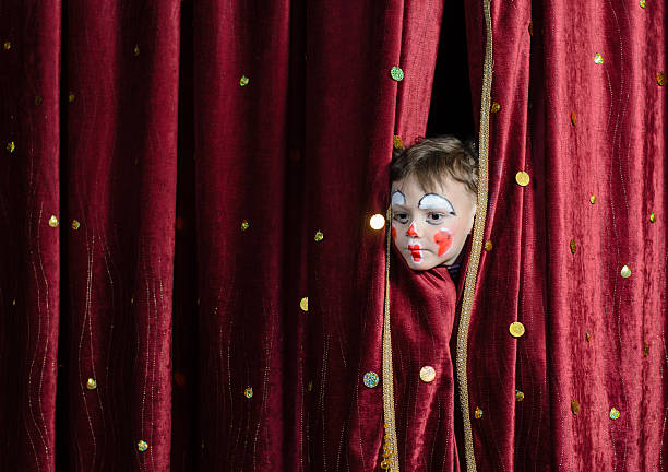 istock Boy Clown Peering Through Stage Curtains 488844768