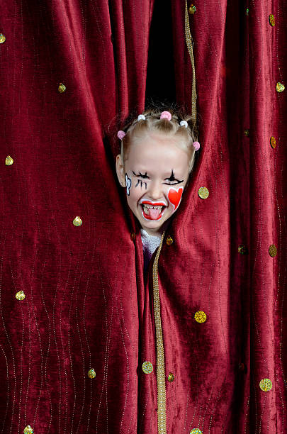 istock Girl Wearing Clown Makeup Peeking Through Curtains 488844910