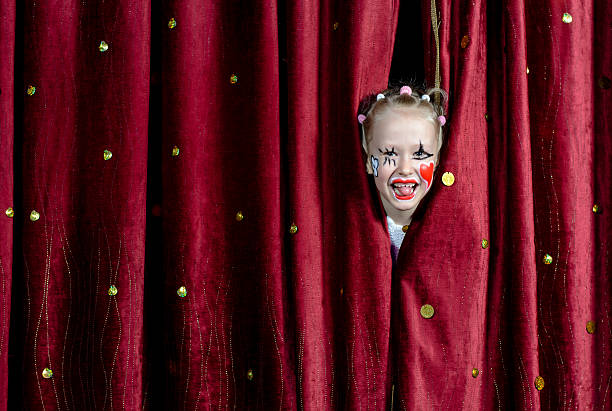 istock Girl Wearing Clown Makeup Peeking Through Curtains 488844948