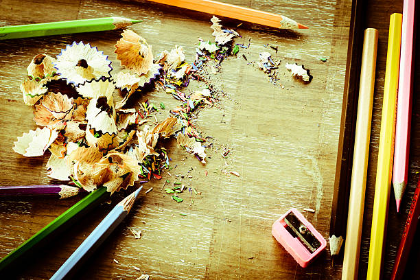 Wooden colorful pencils with sharpening shavings, on wooden table