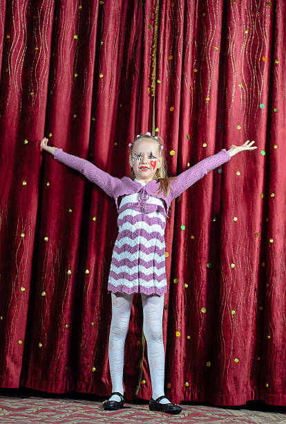 Young girl making her entrance on stage Pretty young blond girl making her entrance on stage during a school play or pantomime standing in her cute little dress with outspread arms in front of the curtain curtain call stock pictures, royalty-free photos & images