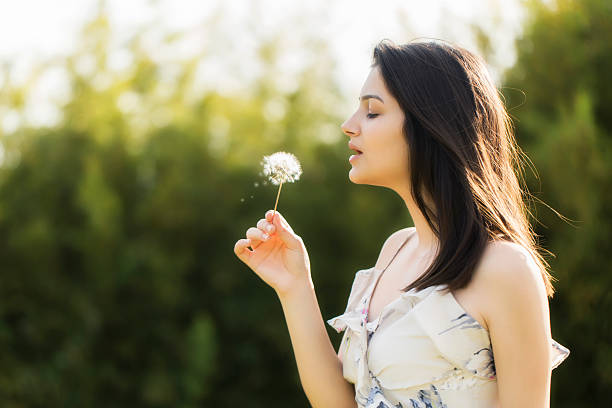 istock Young woman blowing a dandelion 488855389