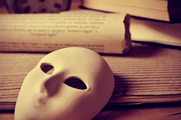 a pile of books and a mask, depicting the concept of playwriting and performing arts
