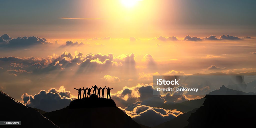 On the top of the world together A group of people standing on a hill over the beautiful cloudscape. Teamwork Stock Photo