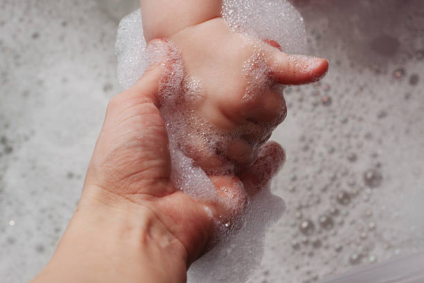 istock mother holds the hand in a bathtub with foam 488870561