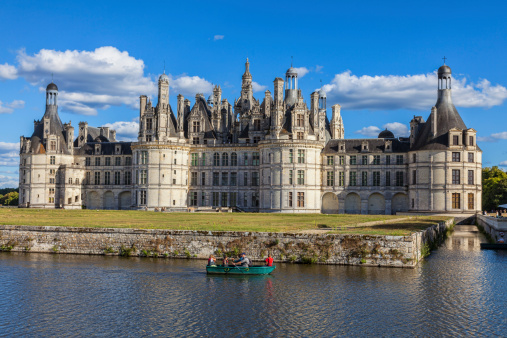 Chambord,France-September 08,2013: A family rowing in a green boat on a canal in front of the Chambord Castle. Chambord is royal medieval French castle in Loire Valley - UNESCO heritage site.