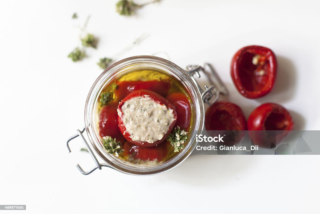 Hot peppers stuffed with tuna, anchovies and capers. preparation of typical Italian craftsmanship spicy peppers stuffed with tuna, anchovies and capers. The product is finished processing, it is put in a jar with olive oil and fresh oregano Tuna - Seafood Stock Photo