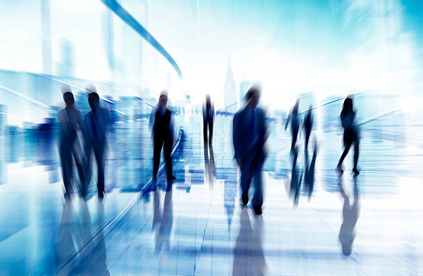 Out of focus silhouettes of men and women Silhouettes of business people in motion.  This image features eight people dressed in business attire.  Their shapes are a blur as they move.  The people are rendered in black, while the abstract background is rendered in light blue, dark blue and white.  Space for text exists at the top and bottom of the frame. defocused office business motion stock pictures, royalty-free photos & images