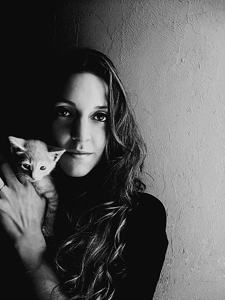 istock young woman holding up a small kitten 488874217