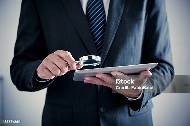 Businessman Holding Magnifying Glass And Digital Tablet Stock Photo - Download Image Now