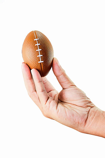 istock hand holding miniaturized rubber rugby ball over white background 488876442