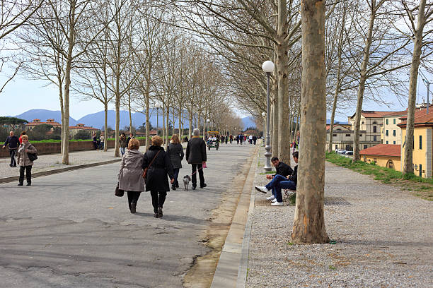 Lucca, Italy - April 1, 2013: Tourists walk on city walls. Lucca is a city in Tuscany, central Italy, famous for its intact city walls from the Renaissance period.