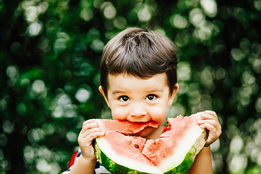 Little boy eating watermelon.