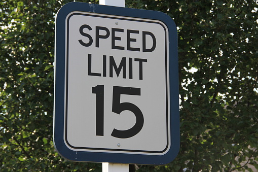 Sign saying 15mph speed limit bordered in teal