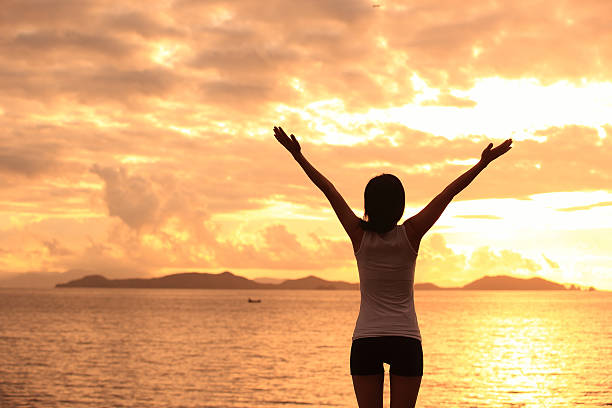 istock cheering woman open arms to sunrise seaside 488889831