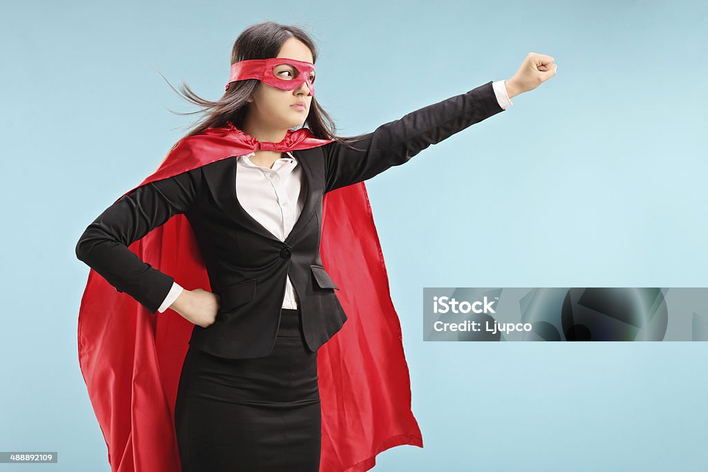 Female superhero with raised fist Female superhero with raised fist on blue background Mask - Disguise Stock Photo