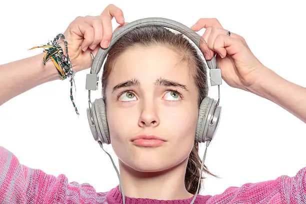 beautiful teenager girl fumble on her headphones, isolated on white.