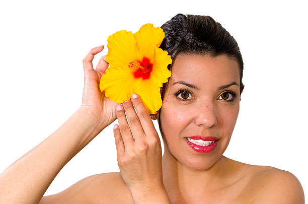 mujer con flores de hibisco en su cabello - facial expression isolated lifestyles exoticism fotografías e imágenes de stock