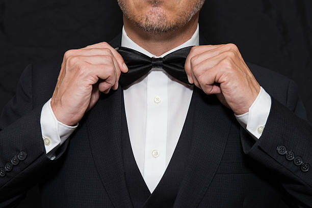 gentleman in black tie straightens his bowtie - 禮服 個照片及圖片檔
