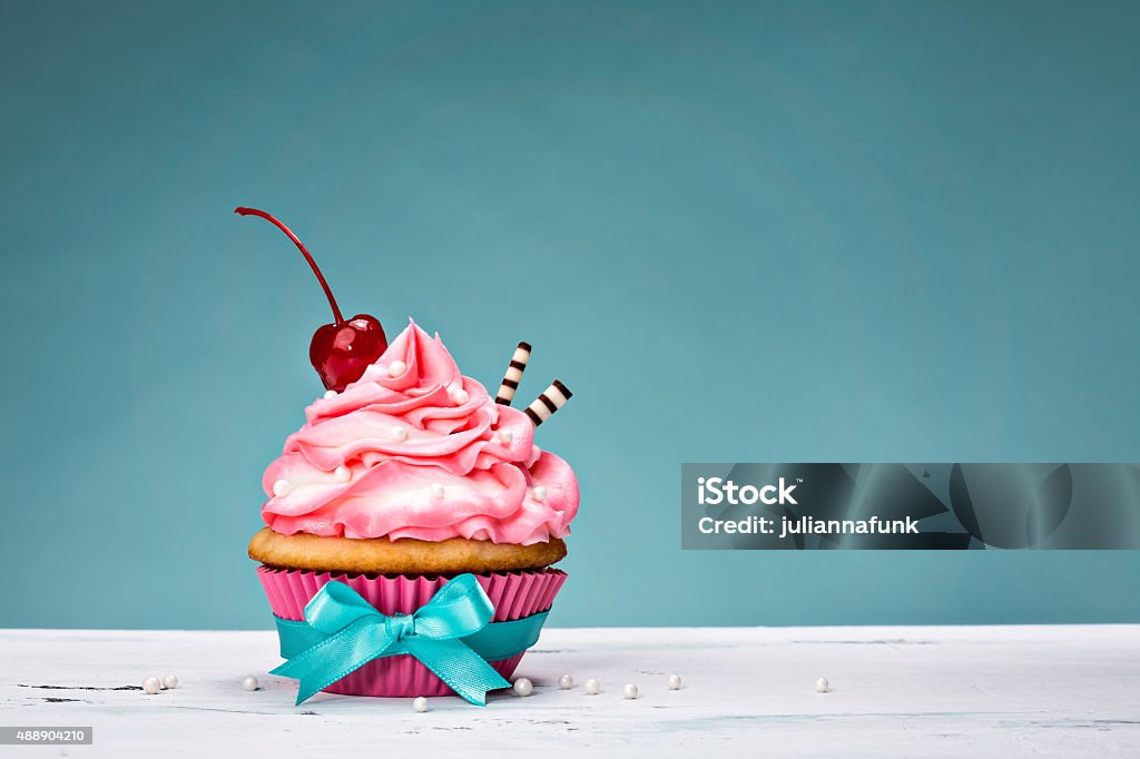 Vintage Cupcake with Cherry on Top Cupcake with pink buttercream icing and a cherry on top. Cherry Stock Photo