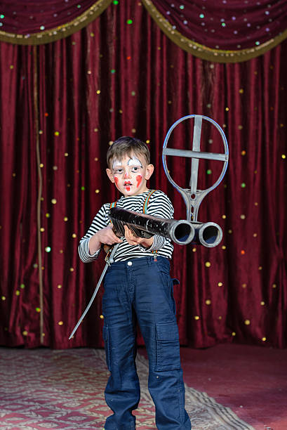 istock Young Male Clown Aiming Large Rifle on Stage 488904536