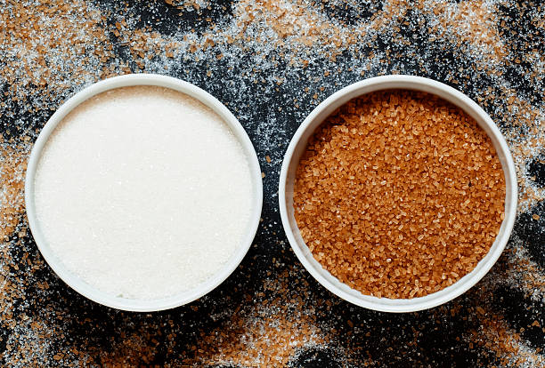istock Cane and white sugar in a porcelain bowl, top view 488907092