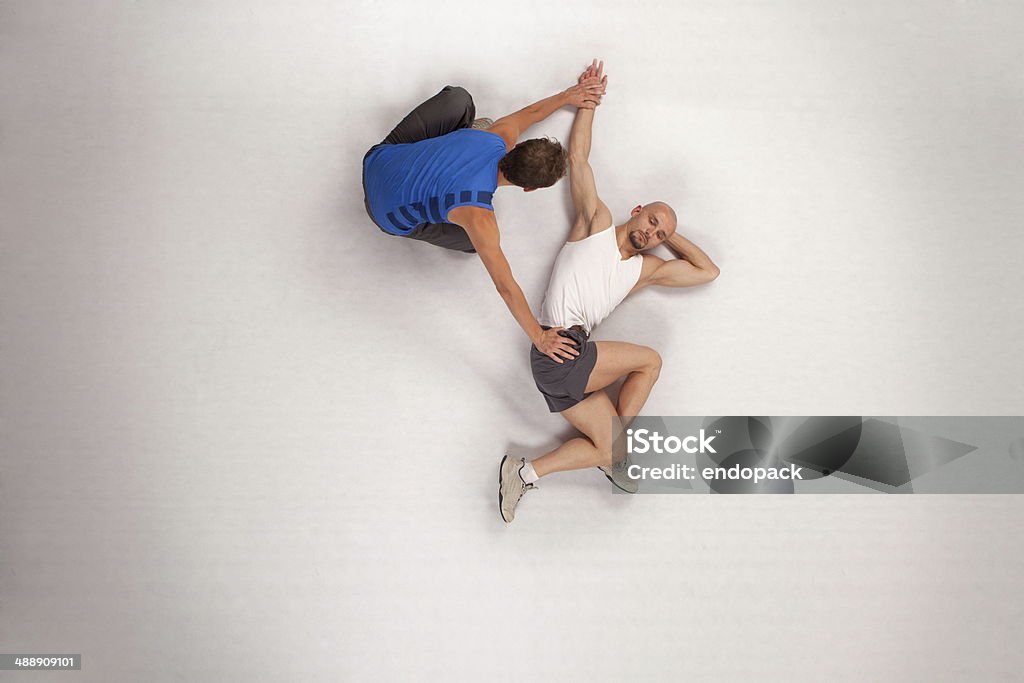 athletic man stretching with personal trainer overhead view of athletic man stretching with personal trainer Exercising Stock Photo