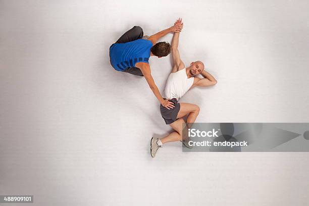 Athletic Man Stretching With Personal Trainer Stock Photo - Download Image Now - Exercising, Human Groin, Relaxation Exercise