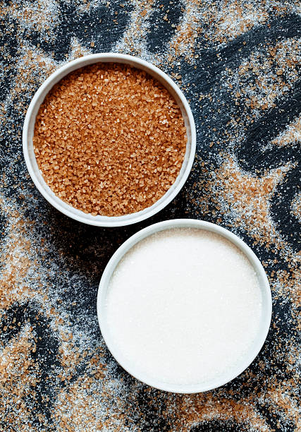 istock Cane and white sugar in a porcelain bowl, top view 488909628